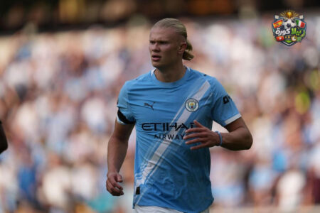 صورة لإرلينج هالاند بقميص مانشستر سيتي مع شعار برشلونة في الخلفية